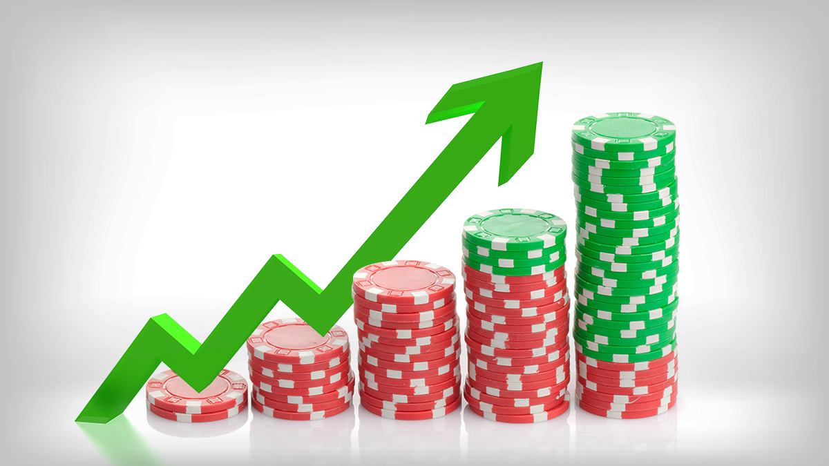 Green arrow rising above a stack of growing poker chips